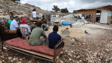 Palestinians sit near the remains of a demolished house on August 10, 2020 near Jenin in the occupied northern West Bank village of Farasi. (AFP)