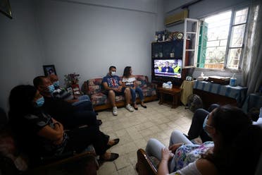 Family members of Ghassan Hasrouty, a missing silo employee, watch a news channel on television as they wait for information, following Tuesday's blast in Beirut's port area. (Reuters)