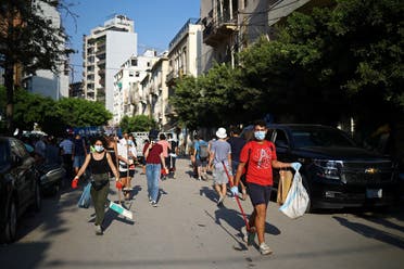 People walk as they clean a street near the site of Tuesday's blast in Beirut's port area, Lebanon. (Reuters)