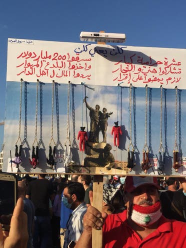 A Lebanese protester holds up a sign with figurines representing the political class, in Beirut on August 8, 2020. (Emily Judd)