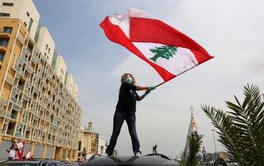 An anti-government demonstrator holds a Lebanese flag as she stands on top of her car in Beirut. (Reuters)
