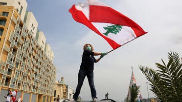 An anti-government demonstrator holds a Lebanese flag as she stands on top of her car in Beirut. (Reuters)