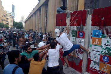 Protesters try to remove a concrete slab from a barrier to open a road leading to the parliament building during an anti-government protest on Aug. 10, 2020. (AP)
