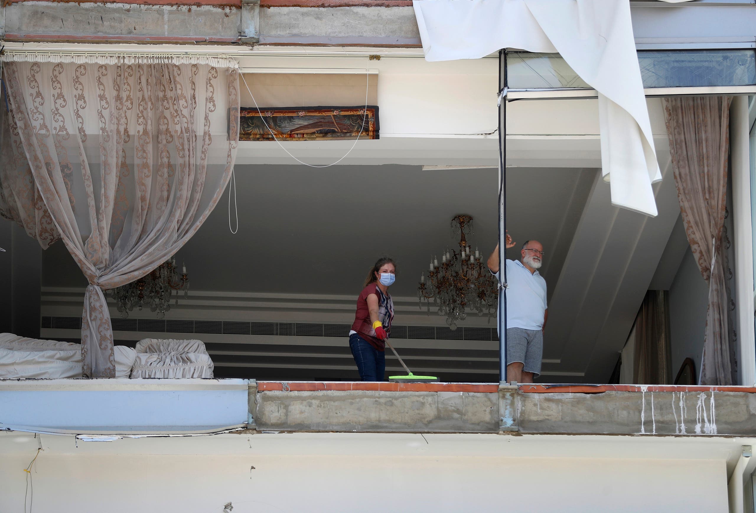 A woman cleans debris from her damaged apartment a day after an explosion hit the seaport of Beirut on Aug. 5, 2020. (AP)