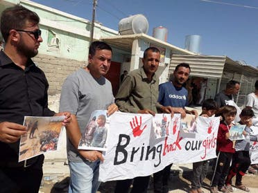 Yazidi men hold up a sign Bring back our girls. (Naji Khadida)
