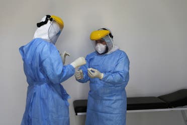 A member of a medical team wearing a protective suit carries a test tube after taking a swab from a man to test for the coronavirus disease (COVID-19), at a medical clinic in Tripoli, Libya June 10, 2020. (Reuters)