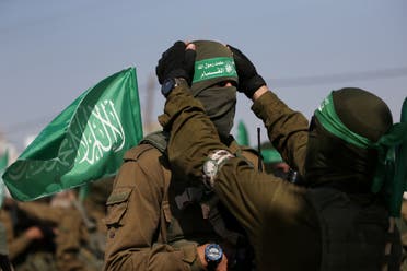 A Palestinian Hamas militant adjusts the mask and headband of his comrade during an anti-Israel military show in the southern Gaza Strip November 11, 2019. (Reuters)