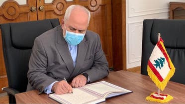 A handout picture provided by the Iranian Foreign Ministry on August 9, 2020 shows Foreign Minister Mohammad Javad Zarif signing a memorial note for the victims of the blast at the port of Beirut, at the Lebanese embassy headquarters in Iran's capital Tehran. 