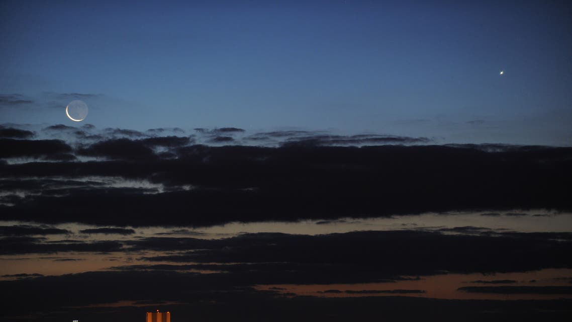 A crecent moon (L) and the planet Venus (R) are seen at dawn over the Vehicle Assembly Building at Kennedy Space Center May 1, 2011 in this view from Titusville, Florida. The once delayed launch of the space shuttle Endeavour has been delayed again until later this week due to problems with an auxiliary power unit heater on the Endeavour. AFP PHOTO/Stan HONDA