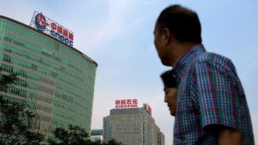 People walk past buildings of China's state-owned companies, China National Offshore Oil Corp. (CNOOC), left, and China Petroleum & Chemical Corp. (Sinopec), in Beijing Monday, Sept. 14, 2015. (AP)
