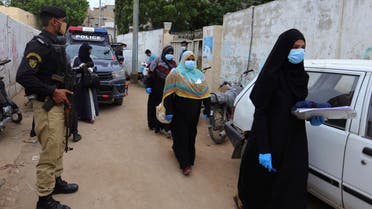 Police officers stand guard while health workers arrive in an area for polio vaccination, in Karachi, Pakistan, Monday, July 20, 2020. (AP)