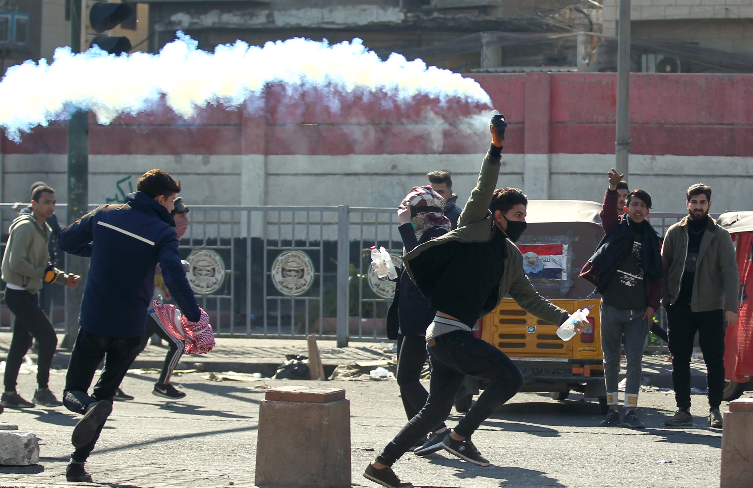 An Iraqi protester grabs a tear gas canister fired by riot police amid clashes following an anti-government demonstration in Al-Khilani Square in Baghdad on January 26, 2020. 