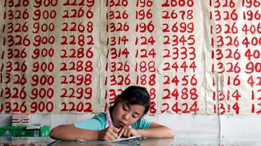 A salesperson waits for customers in front of lists of mobile phone numbers for sale at a shop in Beijing August 11, 2006. (Reuters)
