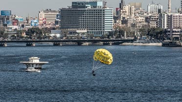 A man parasails in the Nile river during a training session in the Egyptian capital Cairo, on January 26, 2020, with the buildings overlooking the central Tahrir Square seen in the background. (AFP)