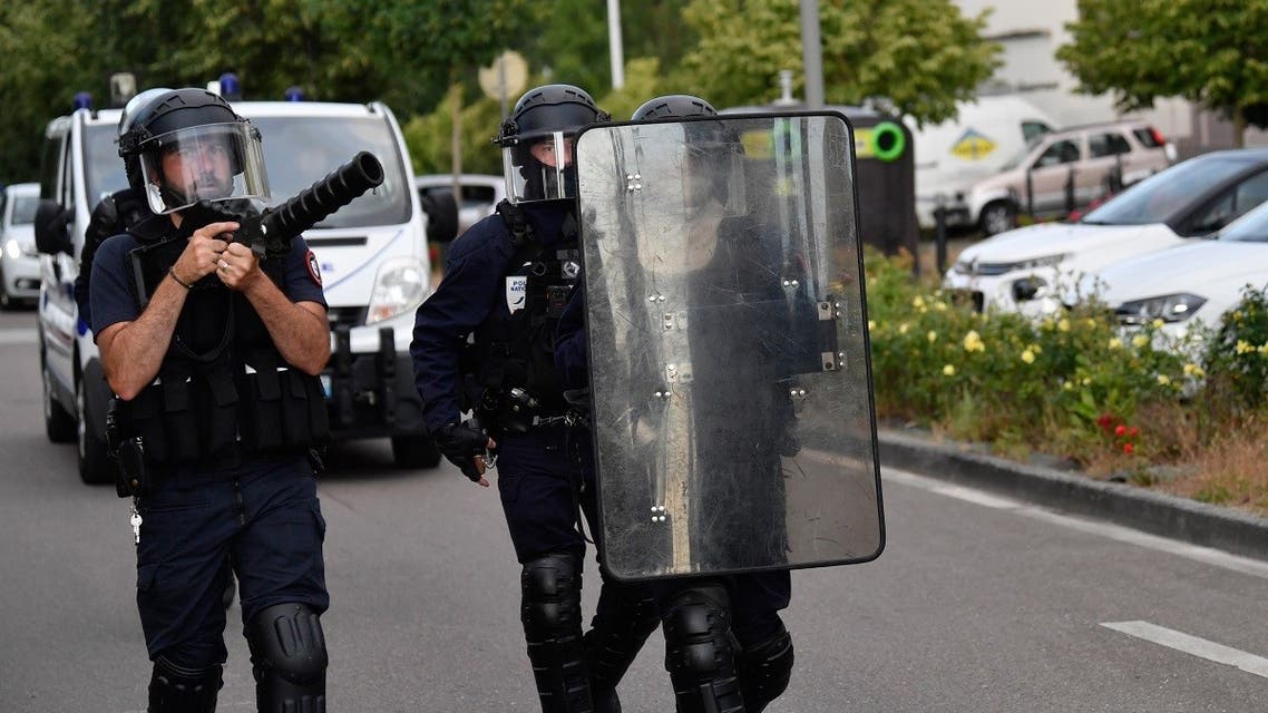 Police walk carrying a shield and a tear gas canister launcher in the Gresilles area of Dijon, eastern France, on June 15, 2020, as new tensions flared in the city after it was rocked by a weekend of unrest blamed on Chechens seeking vengeance for an assault on a teenager. (AFP)