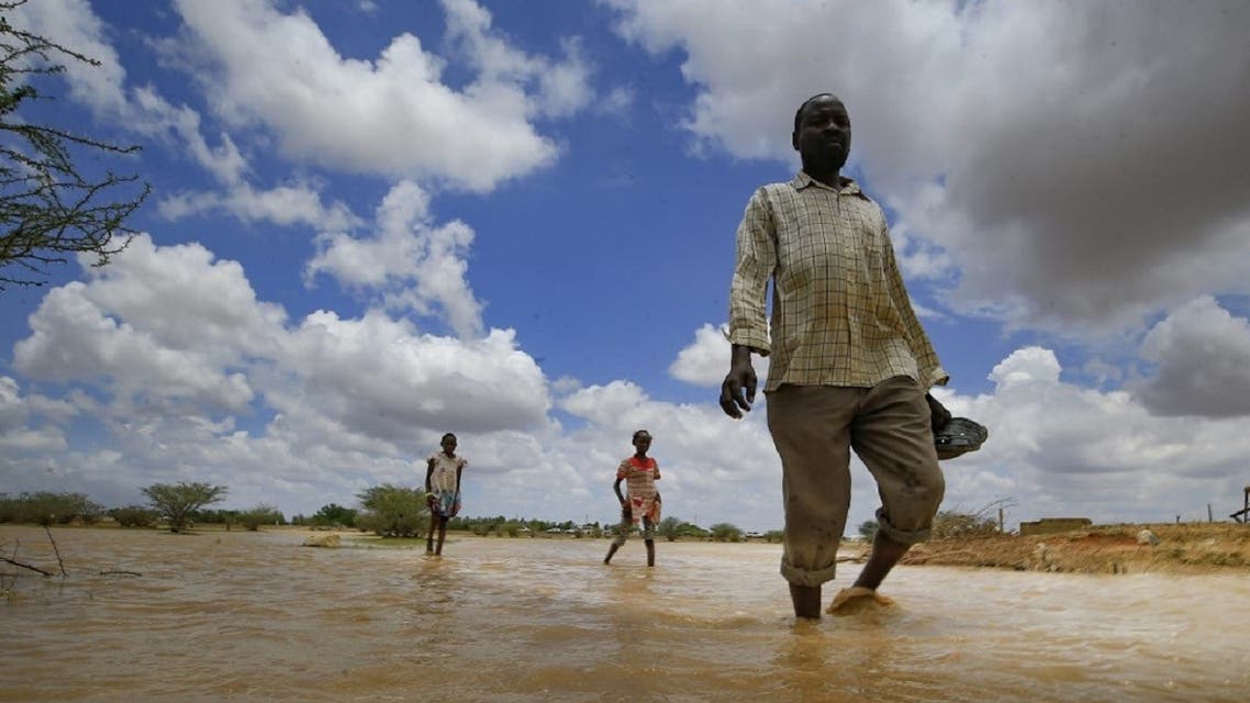 Sudanese men walk in flood water, as a result of flooding and torrential rain, in the town of Osaylat, 50 km southeast of the capital Khartoum, on August 6, 2020. (AFP)
