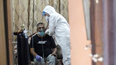 An Iraqi volunteer in a protective suit takes care of a patient infected with coronavirus disease (COVID-19), as he provides him with oxygen at home in the holy city of Najaf, Iraq, August 3, 2020. (Reuters)
