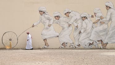 An Emirati man, wearing a protective face-mask, walks past a graffiti in Dubai on March 28, 2020. (AFP)