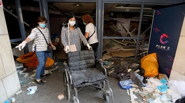 A woman wearing a face mask pushes a wheelchair at a damaged hospital following Tuesday's blast in Beirut Lebanon. (Reuters)