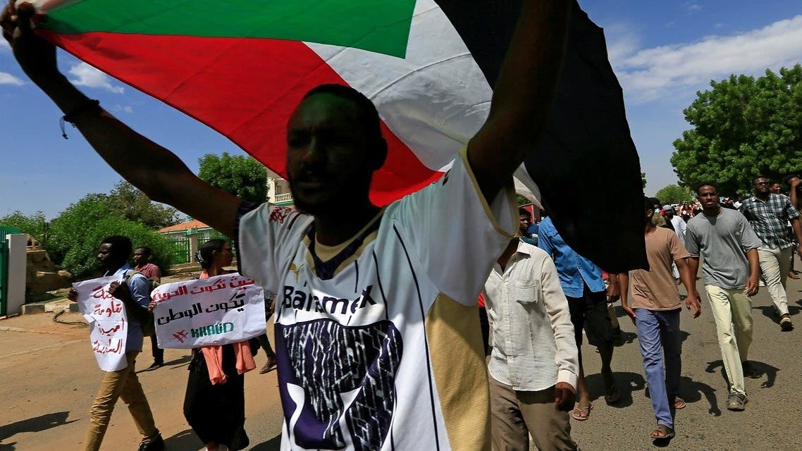 A Sudanese protester carries their national flag as they march in a demonstration to mark the anniversary of a transitional power-sharing deal with demands for quicker political reforms in Khartoum, Sudan, on August 17, 2020. (Reuters)