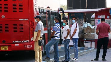 People wearing protective masks wait to board a bus at a station in Kuwait City on August 18, 2020, as businesses reopen after a 5-month shutdown due to the coronavirus. (AFP)