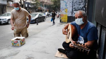 A street musician man performs with a mask on his face to help stop the spread of the coronavirus, as other man on the left puts money on a box, in Beirut, Lebanon on July 29, 2020. (AP)