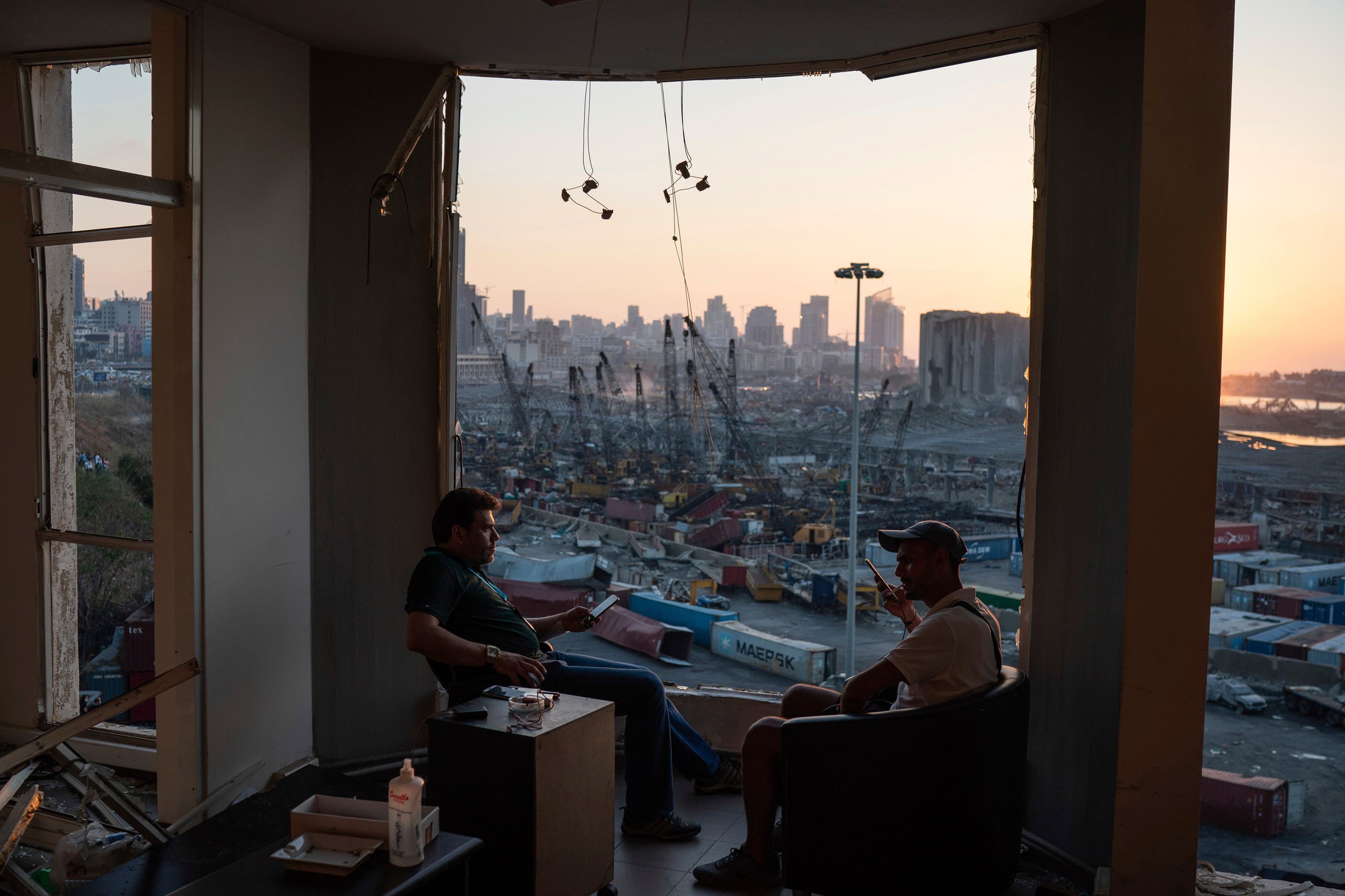 Two men sit on the destroyed balcony of a building facing the site of the massive explosion in the port of Beirut, Lebanon, on Friday, August 14, 2020. (AP)