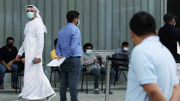 A member of hospital staff watches over people queuing to be tested, amid the coronavirus outbreak, at the Cleveland Clinic hospital in Abu Dhabi, UAE, April 20, 2020. (Reuters)