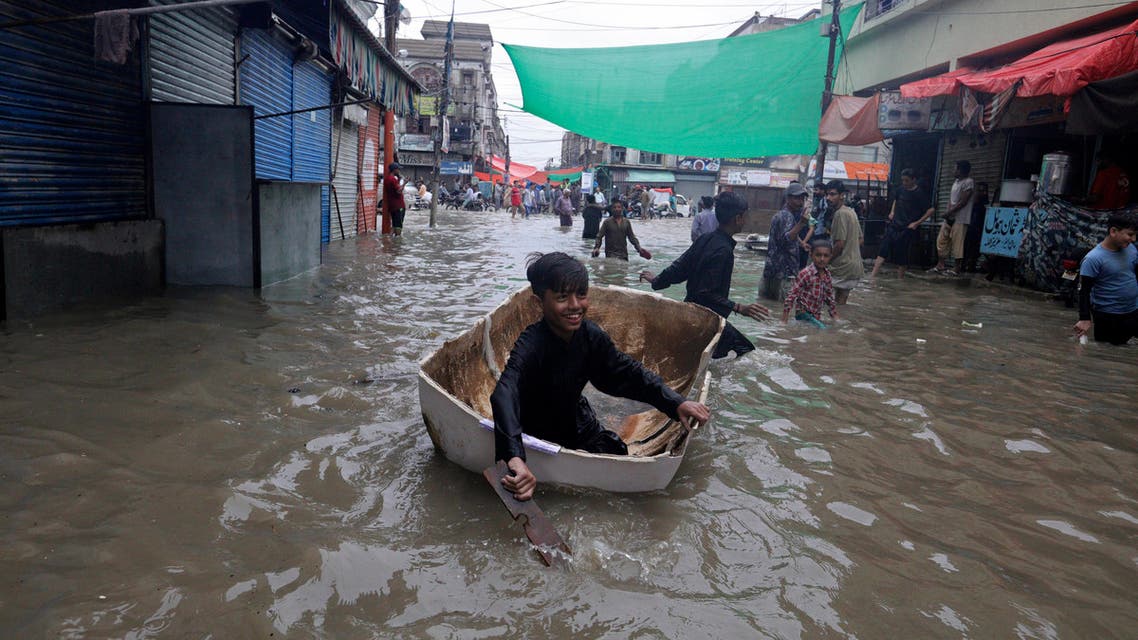 A boy uses half of a fiber tank to navigate a flooded street after heavy monsoon rains, in Karachi, Pakistan on Aug. 27, 2020. (AP)