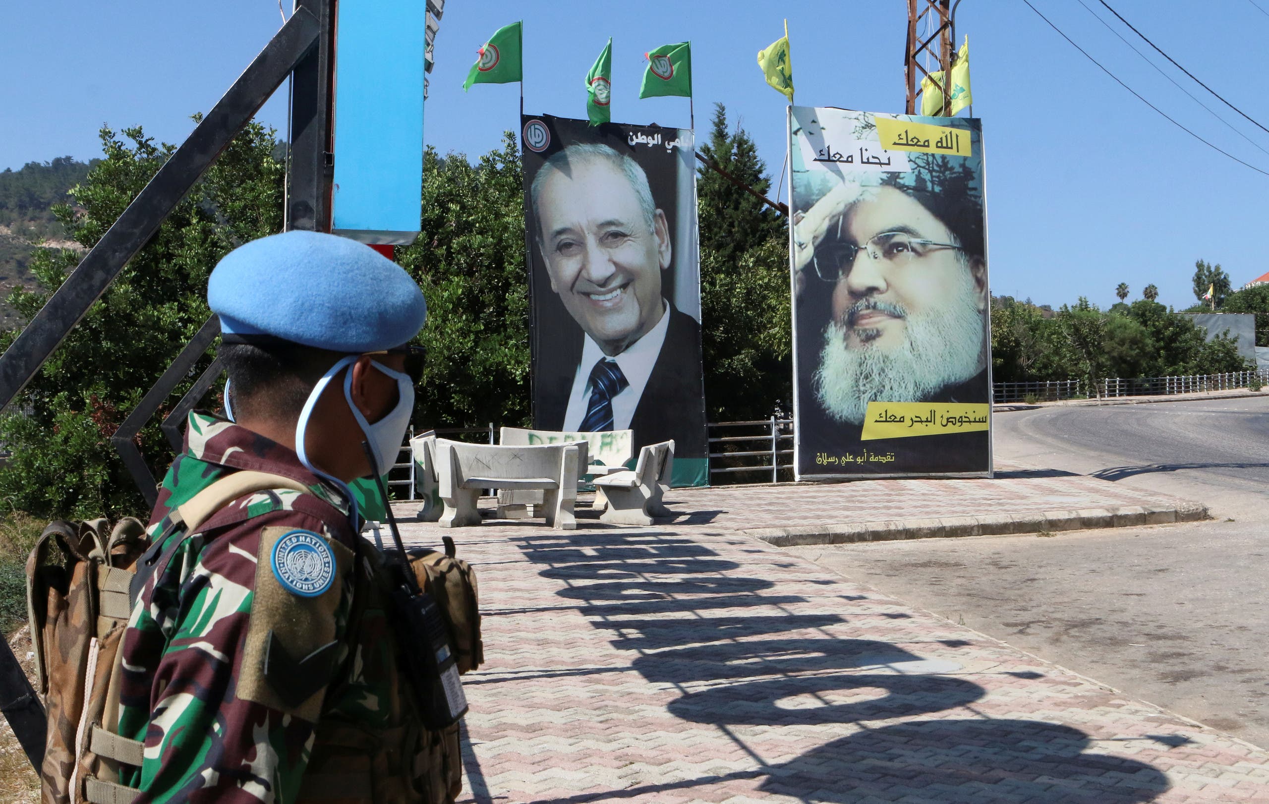 A member of UNIFIL in southern Lebanon in front of photographs of Hezbollah leaders and the Amal Movement