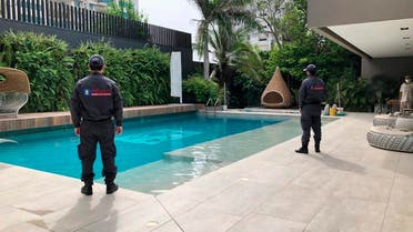officials pose with their backs to the camera by a pool on a property allegedly belonging to Alex Saab in Barranquilla, Colombia. (AP)