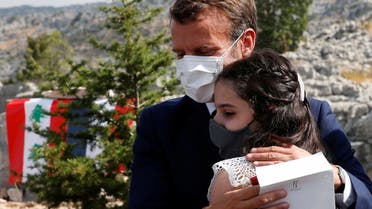 French President Emmanuel Macron hugs blast victim Tamara Tayah after planting a cedar with members of the NGO Jouzour Loubnan in Jaj, near Beirut, September 1, 2020. (AP)