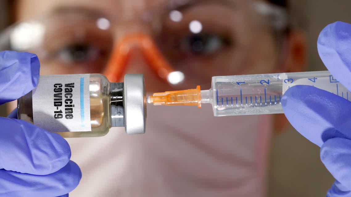 FILE PHOTO: A woman holds a small bottle labeled with a Vaccine COVID-19 sticker and a medical syringe in this illustration taken April 10, 2020. REUTERS/Dado Ruvic/Illustration/File Photo