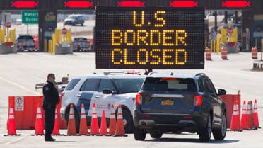 US Customs officers speaks with people in a car beside a sign saying that the US border is closed at the US/Canada border in Lansdowne, Ontario, on March 22, 2020. (AP)