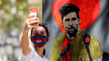 A woman takes a selfie with a mural of Lionel Messi dressed as Che Guevara as FC Barcelona's squad arrive for coronavirus disease (COVID-19) test. (Reuters)