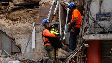 A Chilean rescuer holds a rescue dog as they search in the rubble of a building that was collapsed in Beirut port blast, after getting signals there may be a survivor under the rubble, Beirut, Lebanon, Sept. 3, 2020. (AP)