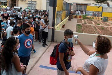 A teacher checks the temperature of a student arriving to a municipal school on the first day of classes for the new academic year in Valencia on September 7, 2020 amid the coronavirus pandemic. (AFP)