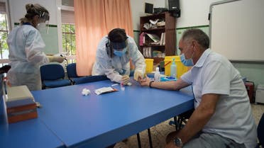 A healthcare worker takes a blood sample from a teacher as staff undergo PCR tests at the Miguel de Cervantes school ahead of its reopening for a new academic year amid the coronavirus pandemic in Ronda on September 1, 2020. (AFP)