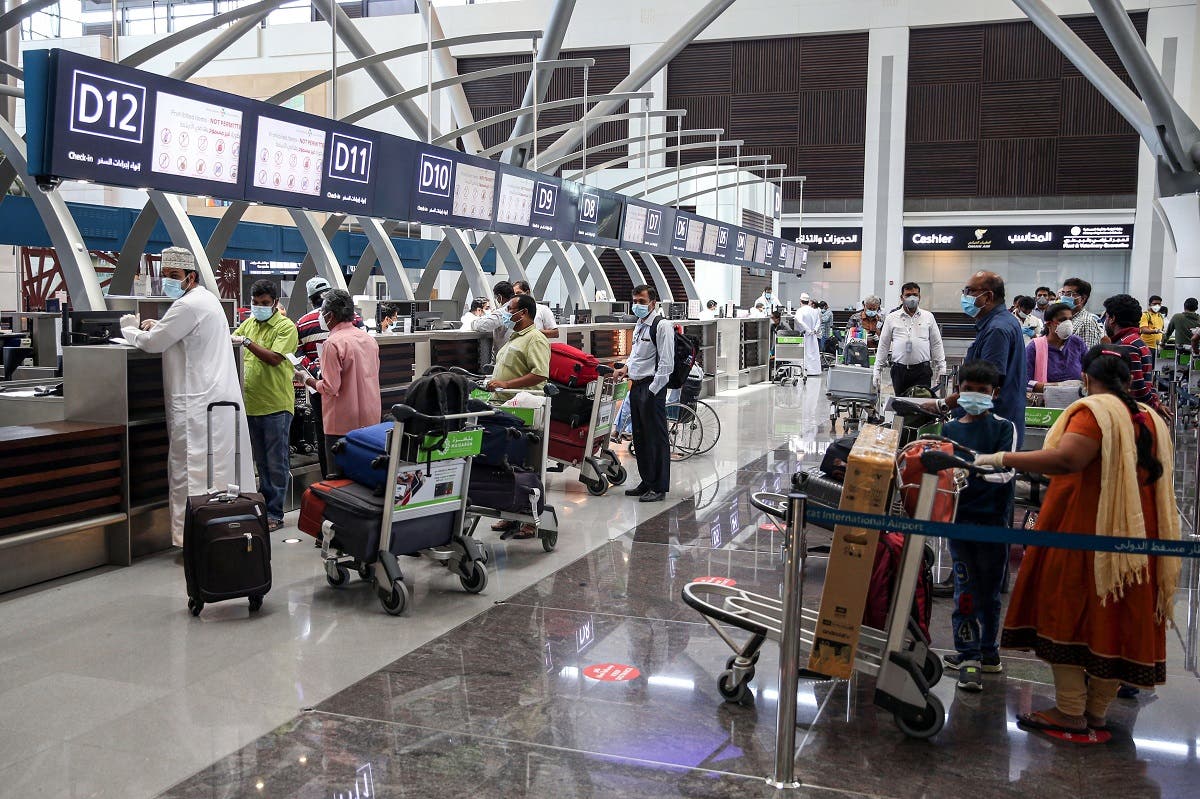 Indian nationals residing in Oman, wearing face masks due to the COVID-19 coronavirus pandemic, queue with their luggage at the check-in counter at a terminal in Muscat International Airport ahead of their repatriation flight from the Omani capital, on May 12, 2020. (AFP)