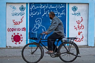 A Syrian man rides a bicycle past a mural painted as part of an awareness campaign by the United Nations International Children's Emergency Fund (UNICEF) and World Health Organization (WHO) initiative on coronavirus in Qamishli, Syria, August 16, 2020. (AFP)