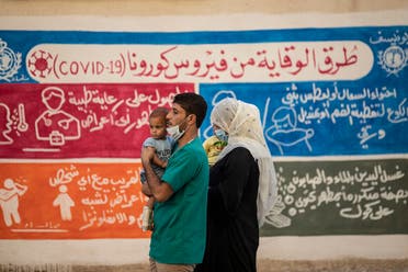 A Syrian family walks past a mural painted as part of an awareness campaign on coronavirus  by the United Nations International Children's Emergency Fund (UNICEF) and World Health Organization (WHO) in Qamishli, Syria, August 16, 2020. (AFP)