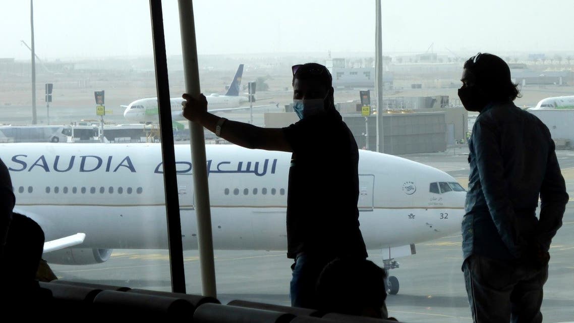 Passengers wear face masks to help curb the spread of the coronavirus as they watch aircraft on the tarmac as they wait for their flight at the King Abdulaziz International Airport in Jeddah. (AP)