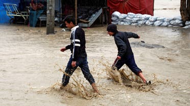 Afghan boys walk through flood waters on a street as heavy rain falls in Kabul, Afghanistan April 16, 2019. (Reuters)