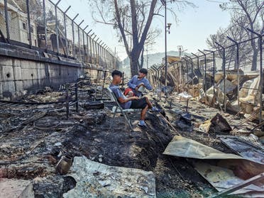 Migrants sit inside the burnt Moria Camp on the Greek island of Lesbos on September 9, 2020, after a major fire. (AFP)