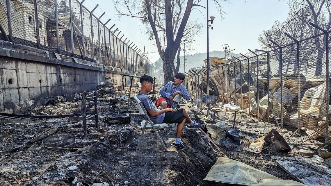 Migrants sit inside the burnt Moria Camp on the Greek island of Lesbos on September 9, 2020, after a major fire. (AFP)