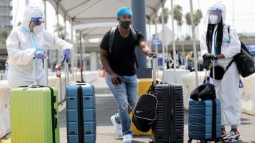 Air travelers (L and R) in personal protective equipment (PPE) at Los Angeles International Airport (LAX) amid the COVID-19 pandemic on August 20, 2020 in Los Angeles, California. (AFP)