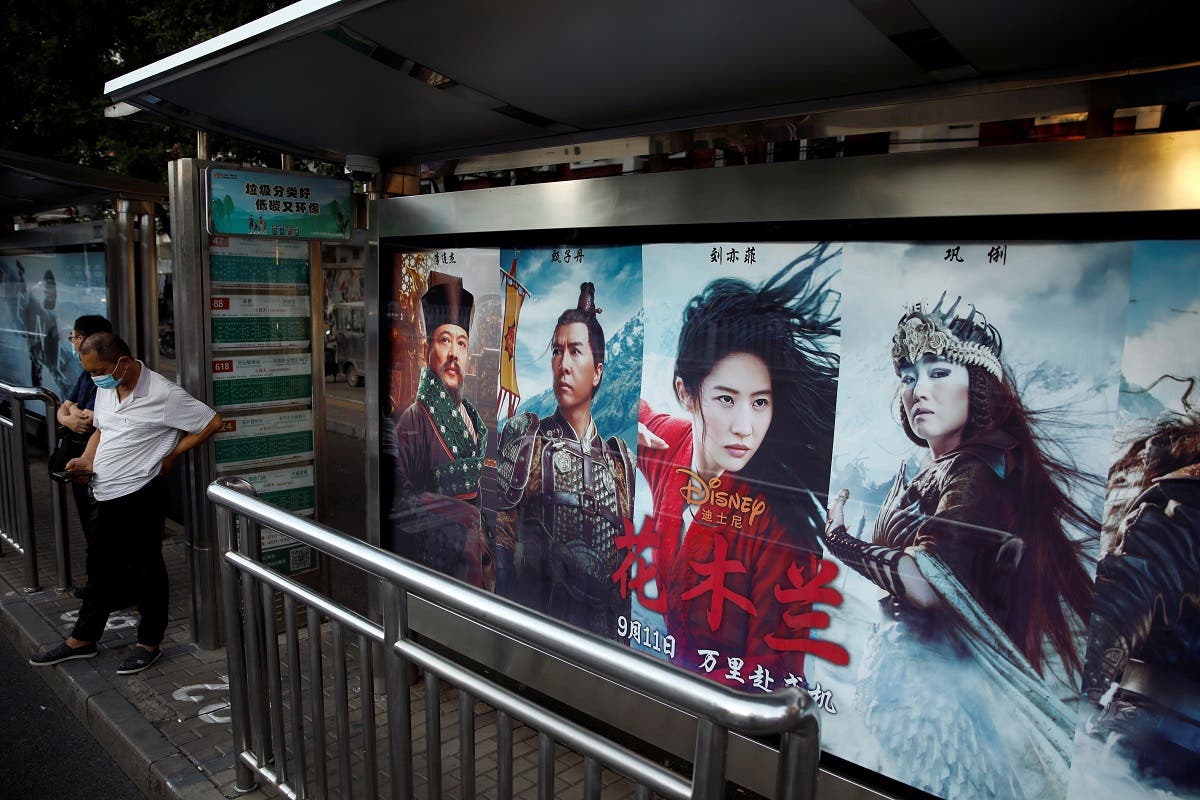 People stand near an advertisement promoting Disney's movie “Mulan” at a bus stop in Beijing, China September 9, 2020. (Reuters)