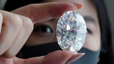 An employee of Sotheby’s poses with a perfect 100+ carat diamond, the second largest oval diamond of its kind to ever appear at an auction which will be auctioned by Sotheby's in Hong Kong in October, in the Manhattan borough of New York City, New York, US, on September 9, 2020. (Reuters)