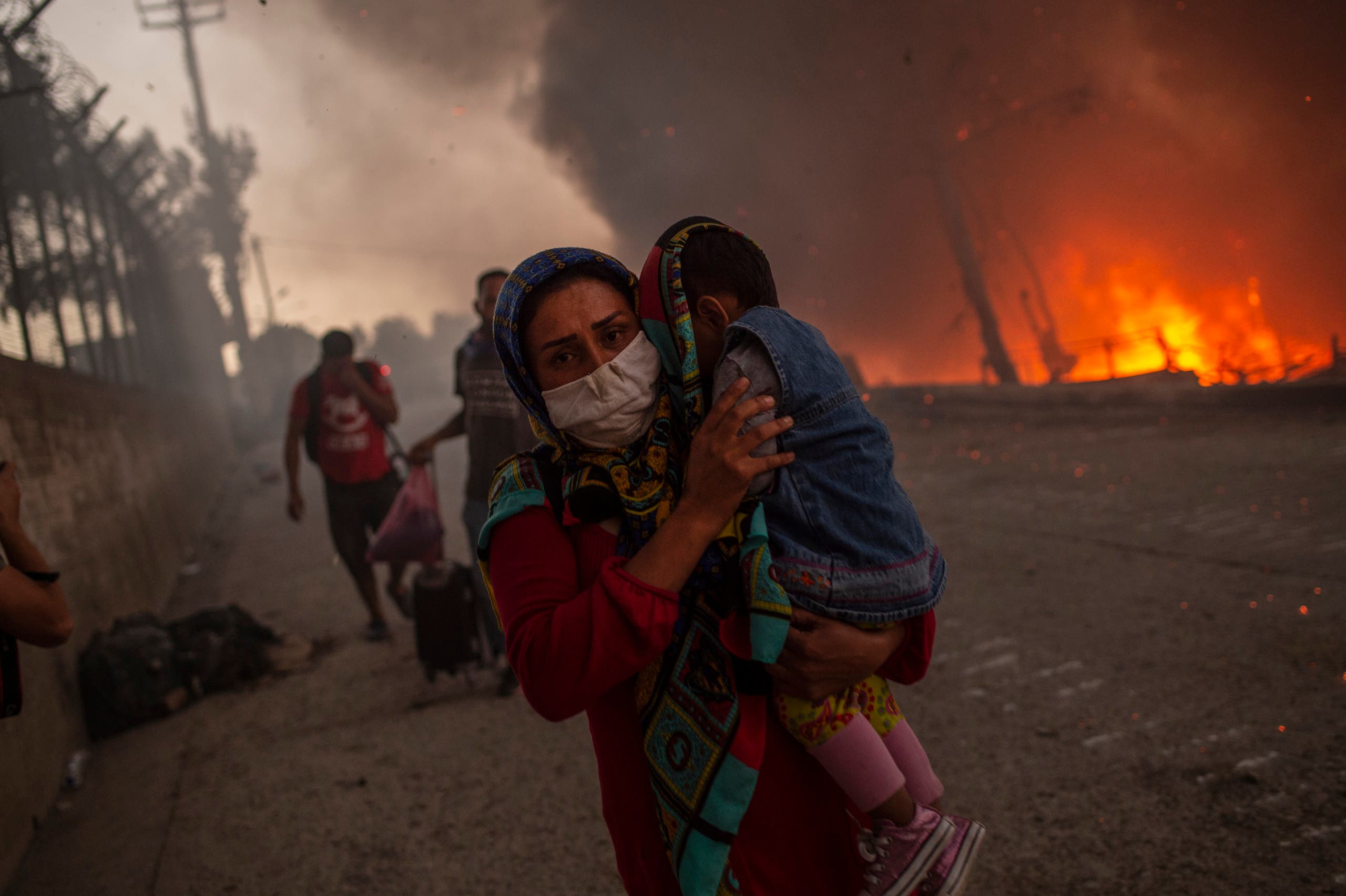 People with children flee flames after a major fire broke out in the Moria migrants camp on the Greek Aegean island of Lesbos. (AFP)