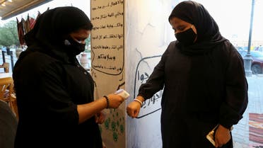 A restaurant's female member of the security personnel wearing a protective face mask, following the outbreak of the coronavirus disease (COVID-19), checks the temperature of a woman before enter the restaurant after reopened, in Riyadh, Saudi Arabia June 13, 2020. Picture taken June 13, 2020. REUTERS/Ahmed Yosri